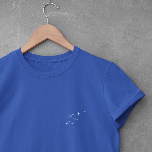 Royal Blue Aquarius constellation t-shirt on a wooden hanger against a gray concrete wall.