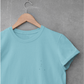 Turquoise Cancer constellation t-shirt on a wooden hanger against a gray concrete wall