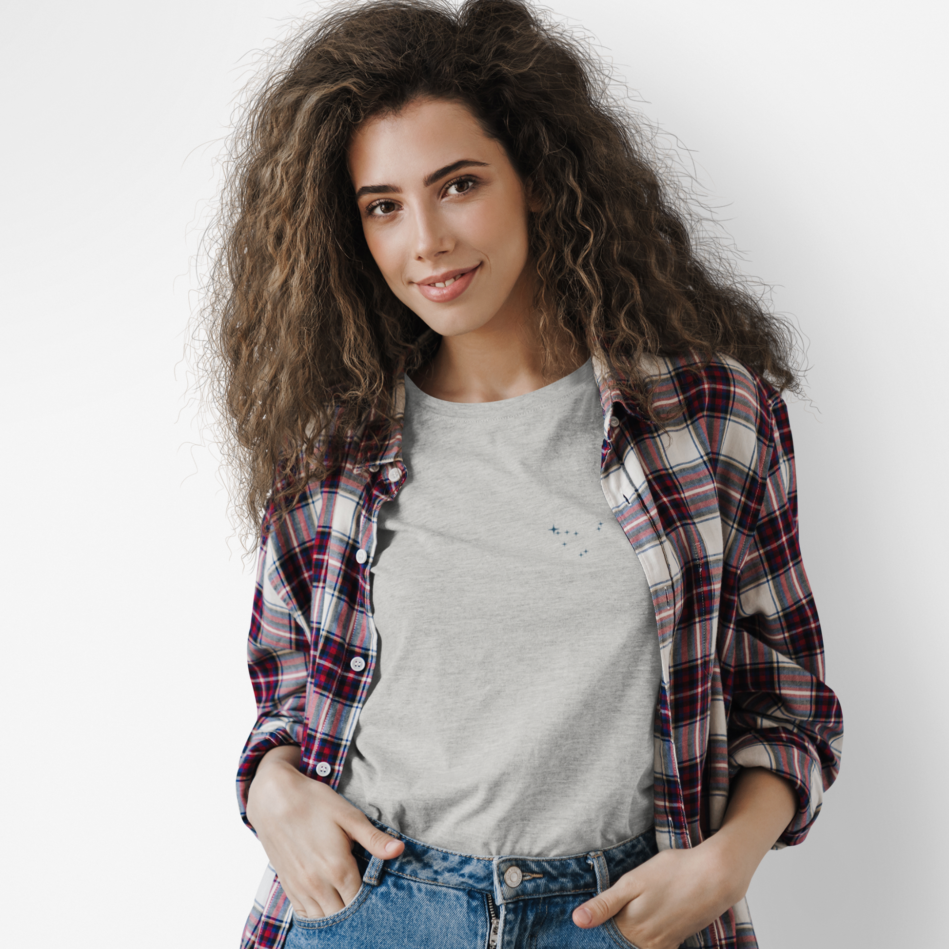 Woman wearing a silver Capricorn constellation tshirt and a flannel with a white background.