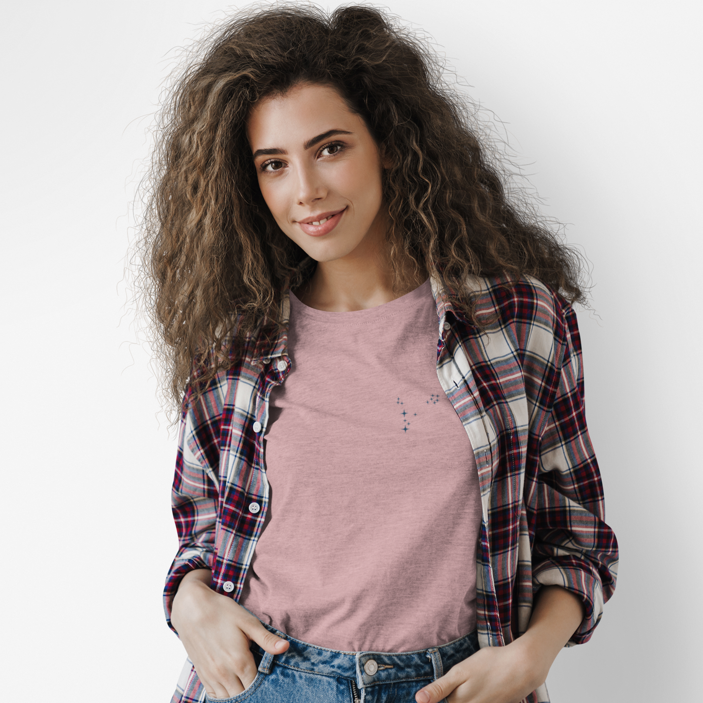 Woman wearing an orchid Pisces constellation tshirt and a flannel with a white background.