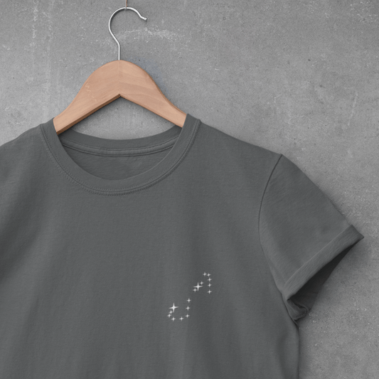 Graphite Scorpio constellation t-shirt on a wooden hanger against a gray concrete wall.
