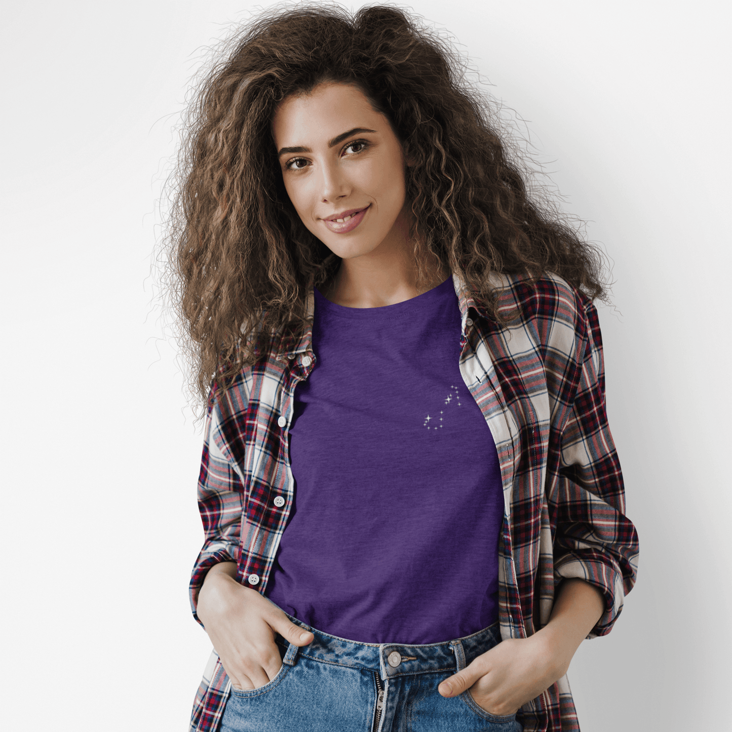 Woman wearing a purple Scorpio constellation t-shirt and a flannel with a white background.