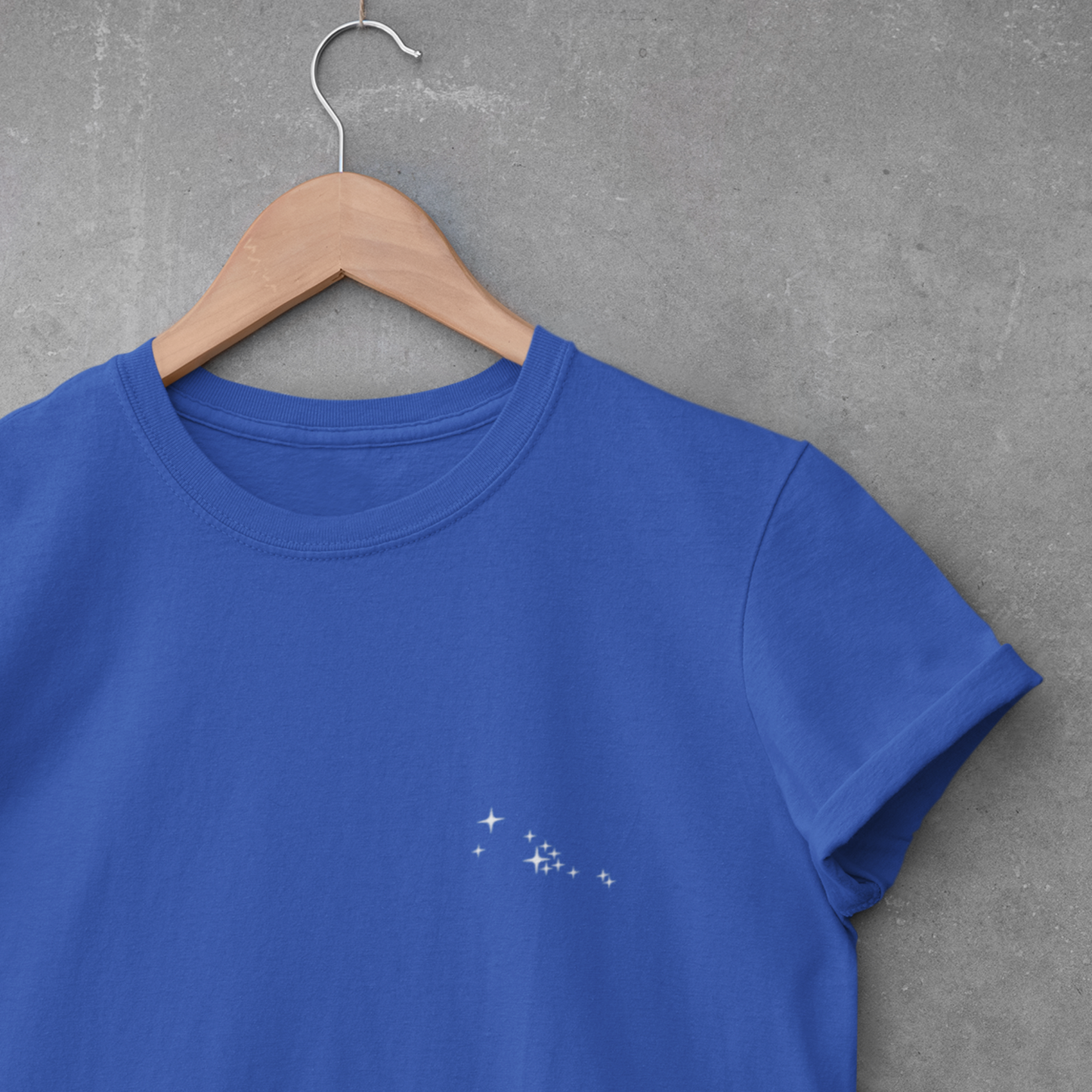 Blue Taurus constellation t-shirt on a wooden hanger against a gray concrete wall.