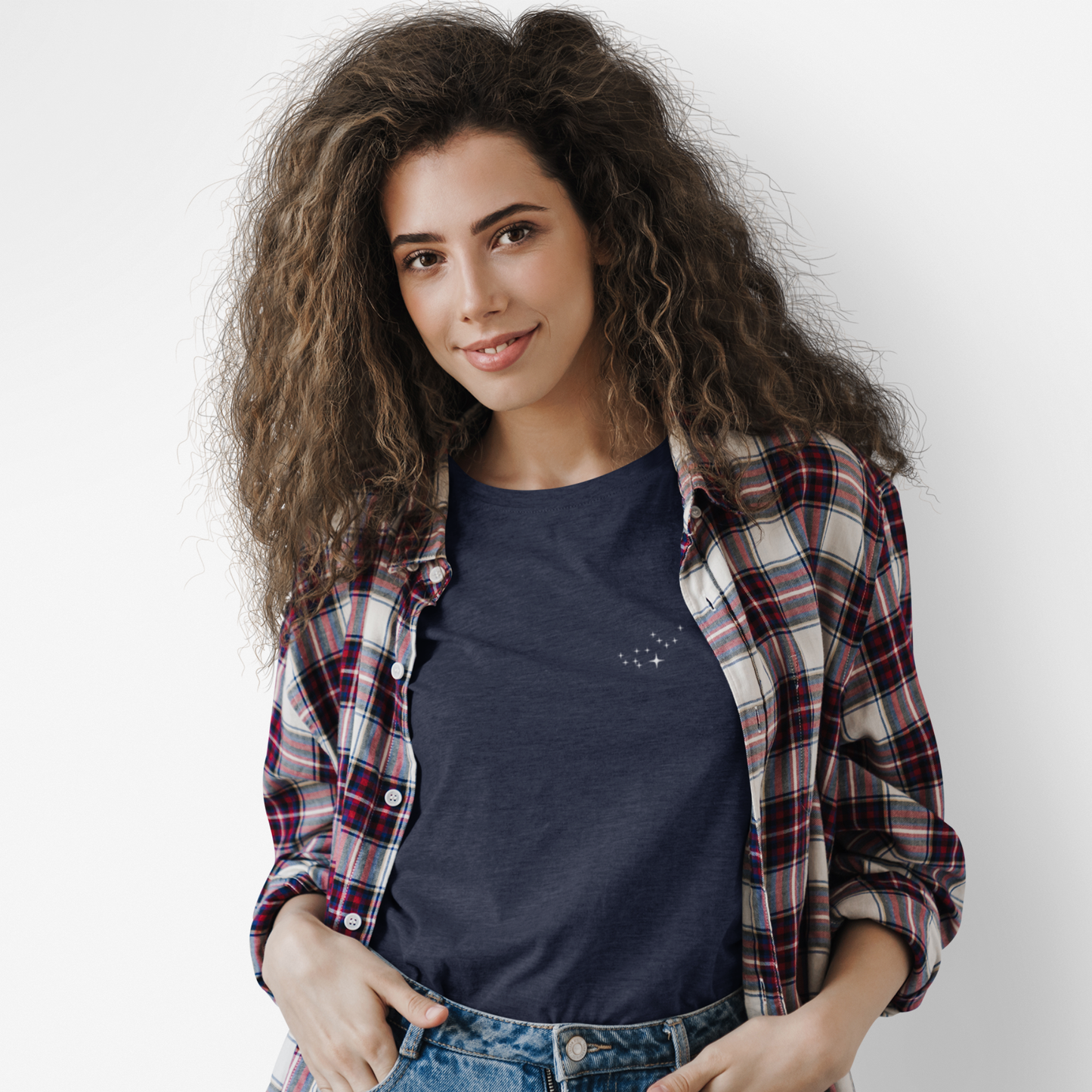 Woman wearing a navy Virgo constellation tshirt and a flannel with a white background.