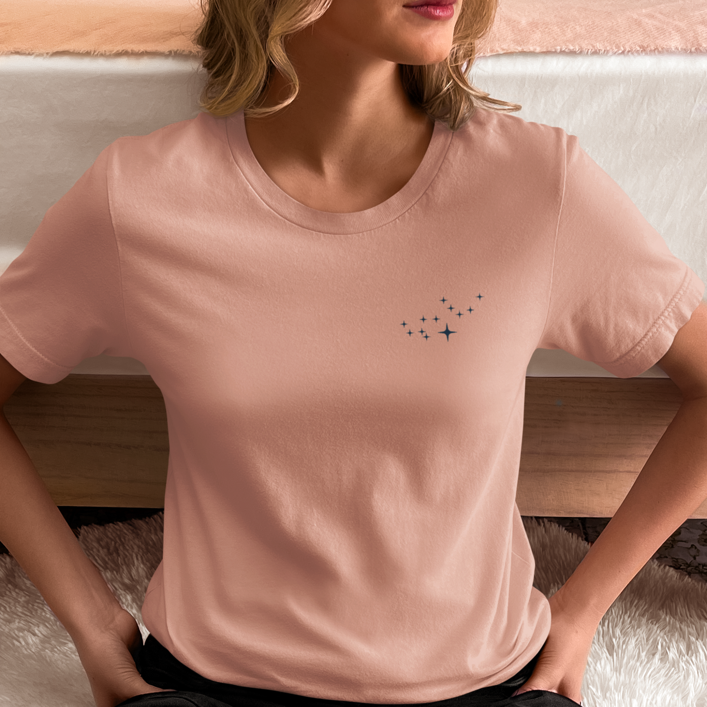 Woman wearing a peach t-shirt with Virgo constellation stars.